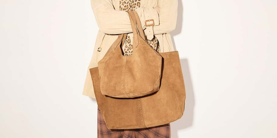 Model wearing a trench coat and plaid pants holding the FREDA SALVADOR AVERY and ABAGAIL Tote in Saddle Suede, styled with a leopard-print scarf for a warm, layered fall look.