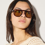 Woman wearing brown sunglasses against a plain background