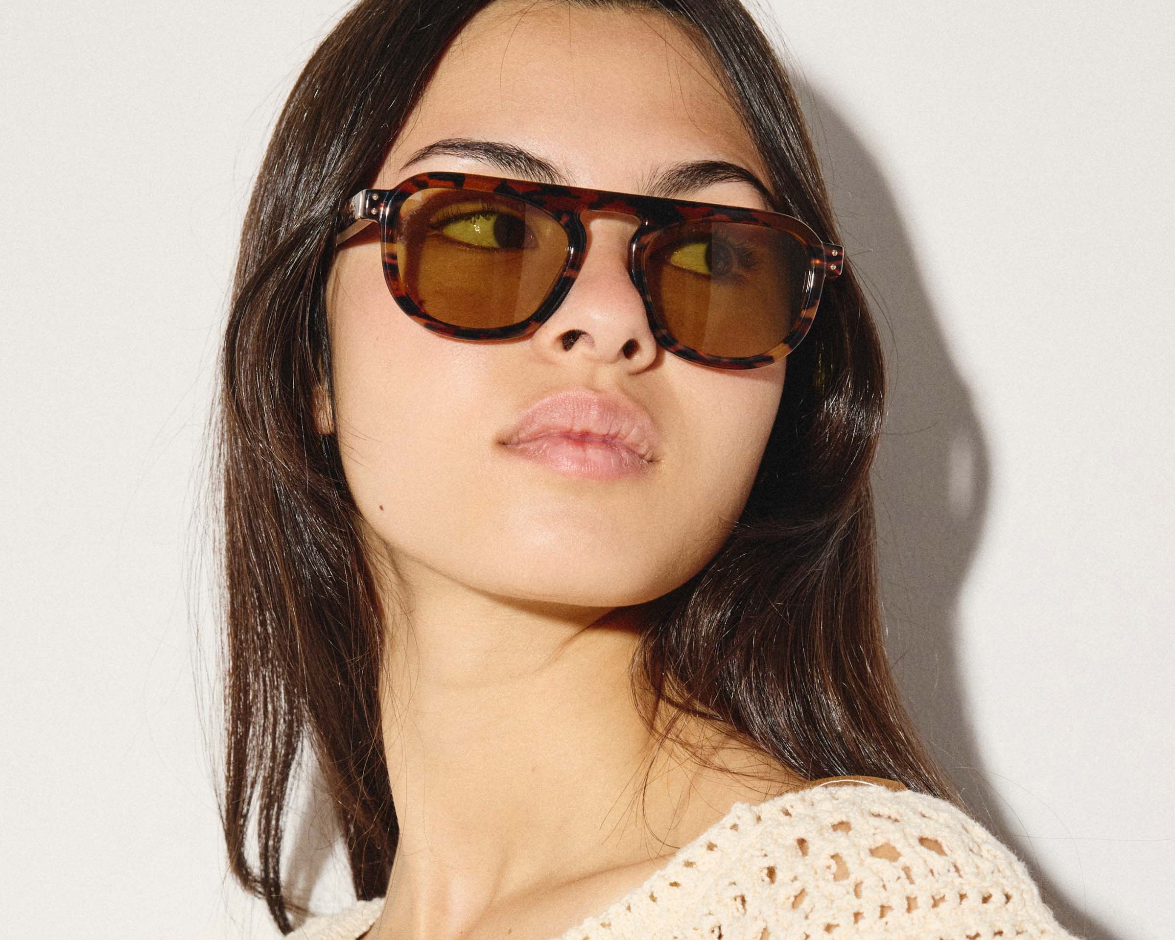 Woman wearing brown sunglasses against a plain background