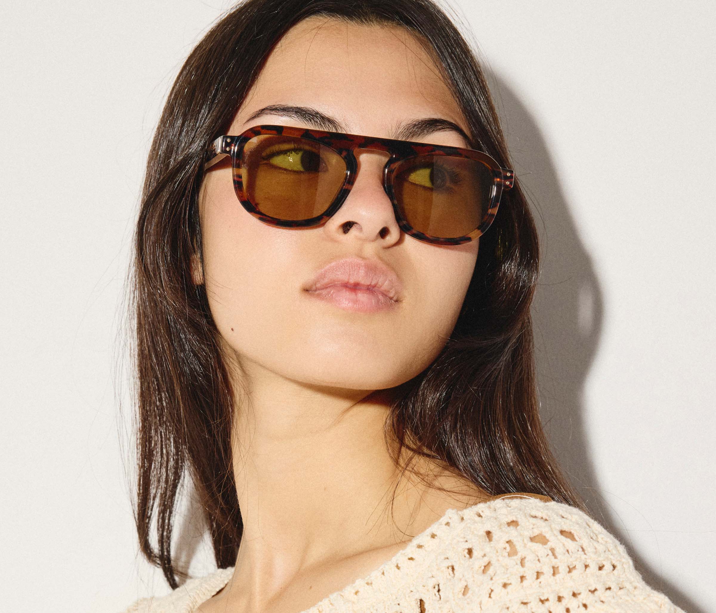 Woman wearing brown sunglasses against a plain background