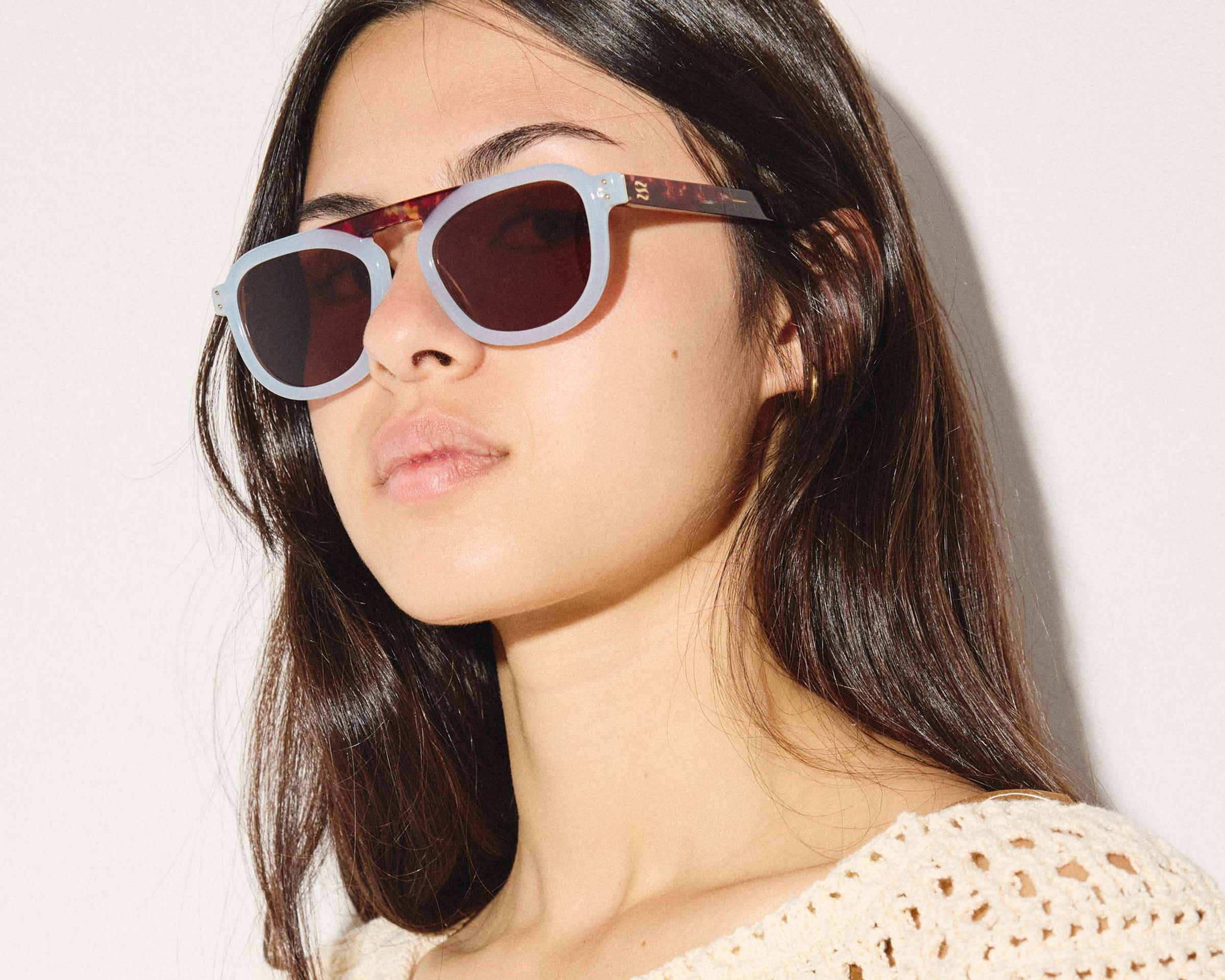 Woman wearing a pair of sunglasses with a neutral background