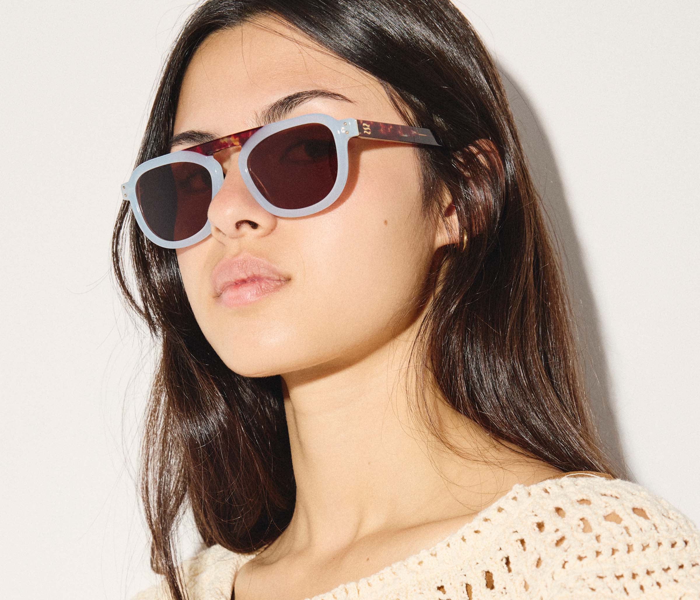 Woman wearing a pair of sunglasses with a neutral background