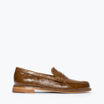 A single brown crocodile-embossed leather penny loafer shown in profile against a clean white background.