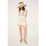 Woman wearing a white dress and straw hat on a plain background