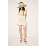 Woman wearing a white dress and straw hat on a plain background