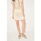 Person wearing a beige crochet dress on a white background