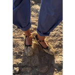 woman wearing Lorna Murray x Freda Salvador shoes with black bows on a sandy surface