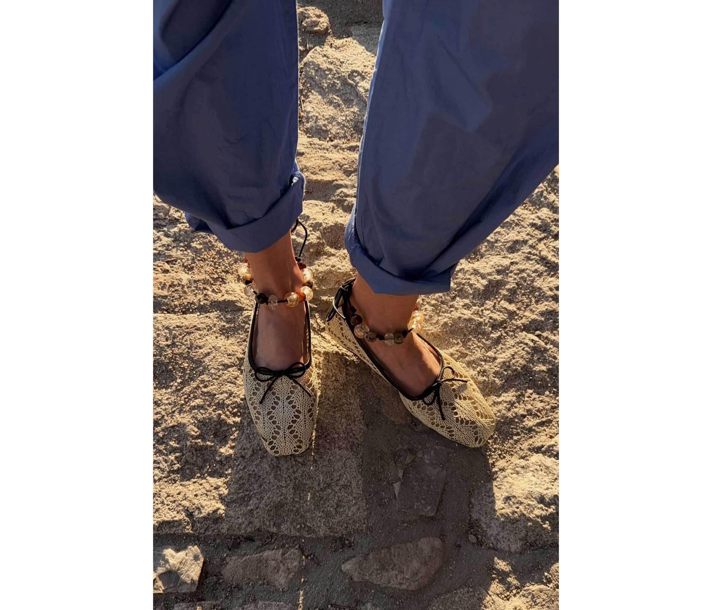 woman wearing Lorna Murray x Freda Salvador shoes with black bows on a sandy surface