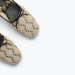 Pair of beige lace-up flats on a light gray background