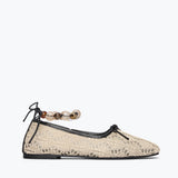 Beige flat shoe with lace details and a decorative ankle strap on a white background