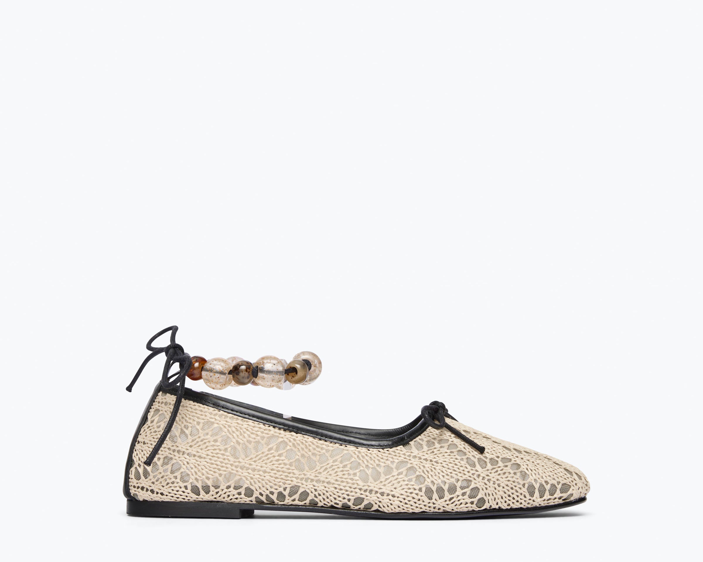 Beige flat shoe with lace details and a decorative ankle strap on a white background