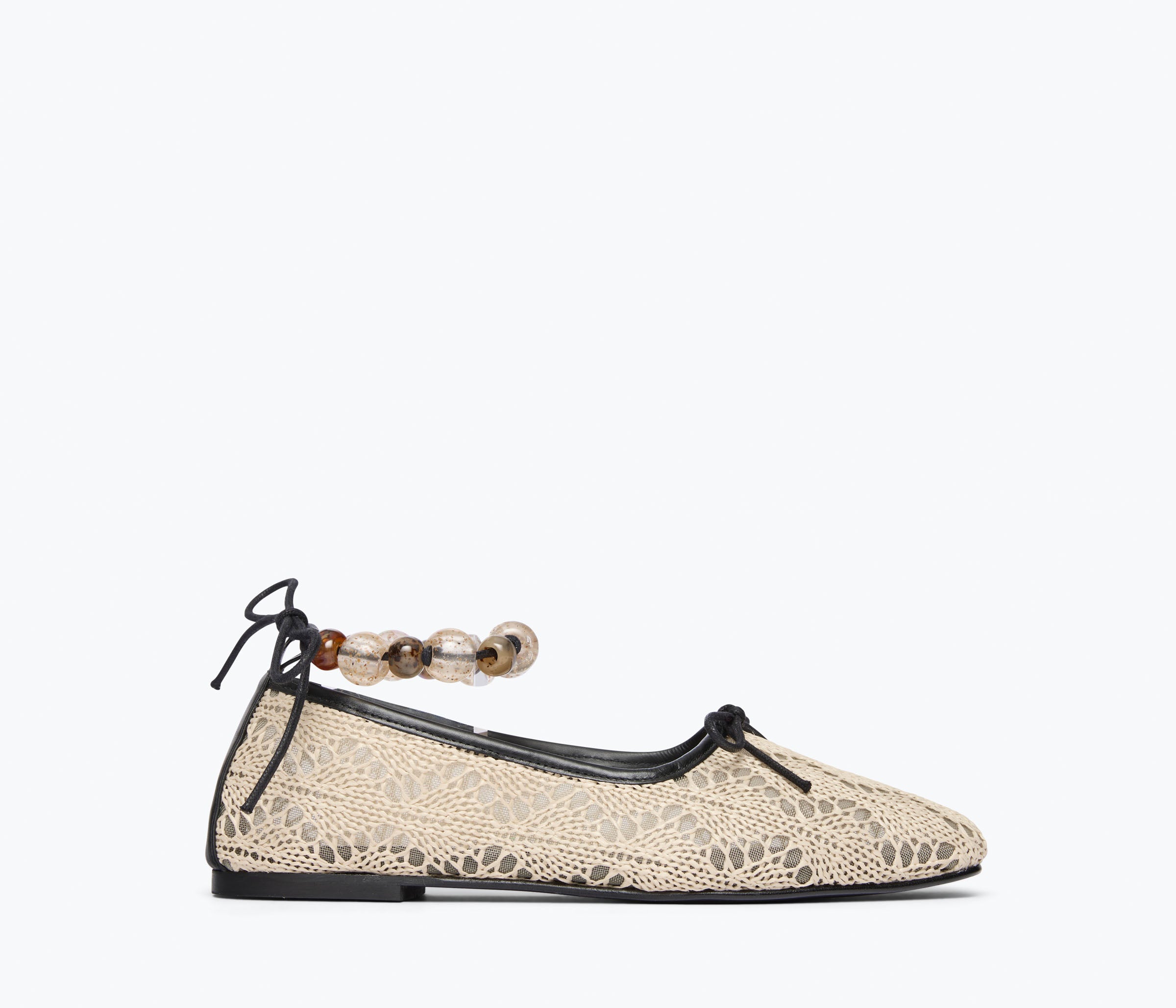 Beige flat shoe with lace details and a decorative ankle strap on a white background