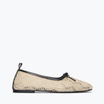 Beige lace flat shoe with black trim on a white background
