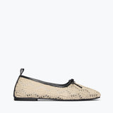 Beige lace flat shoe with black trim on a white background