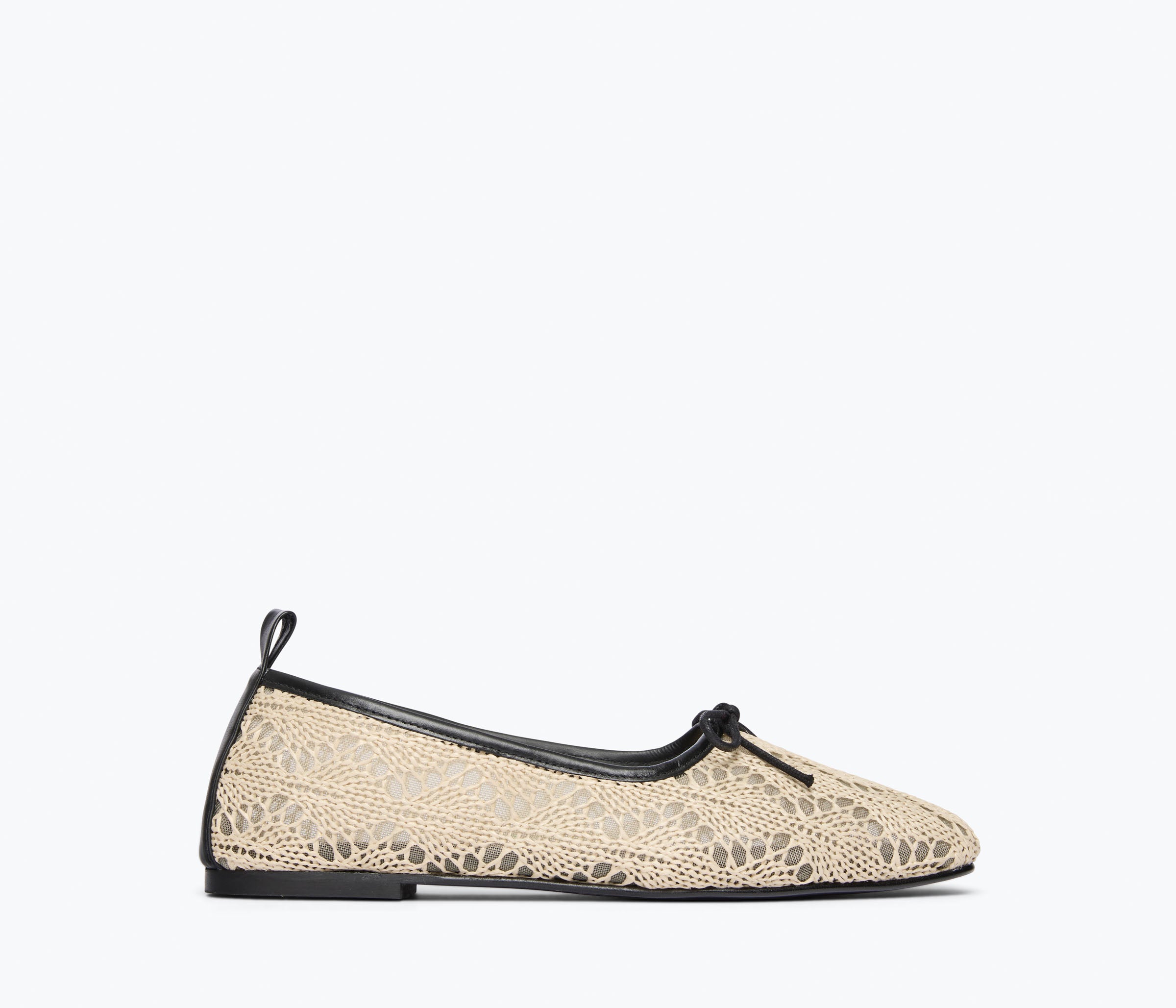 Beige lace flat shoe with black trim on a white background