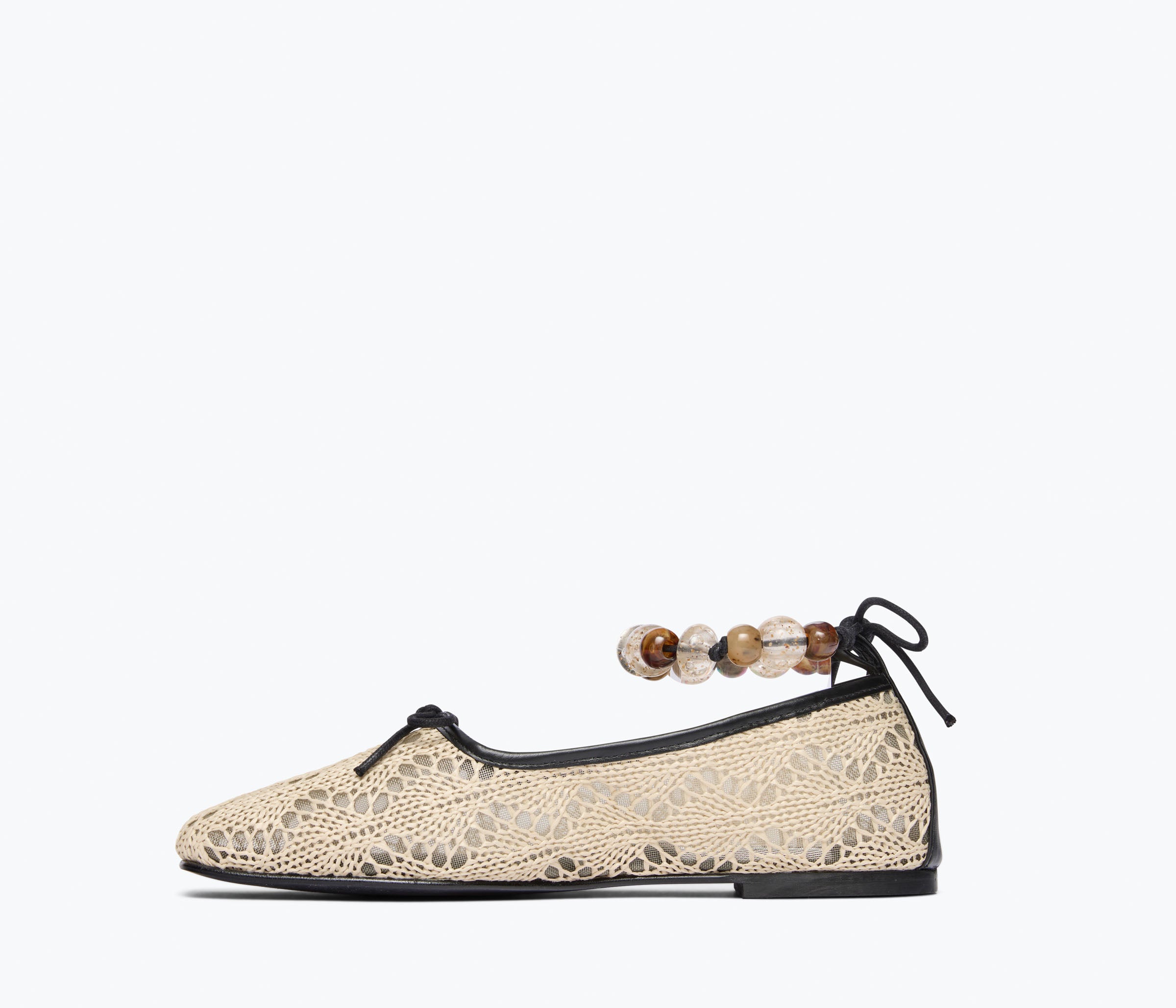 Beige flat shoe with lace design and wooden beads on a white background