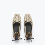 Pair of beige lace-up shoes with black soles on a white background