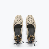 Pair of beige lace-up shoes with black soles on a white background