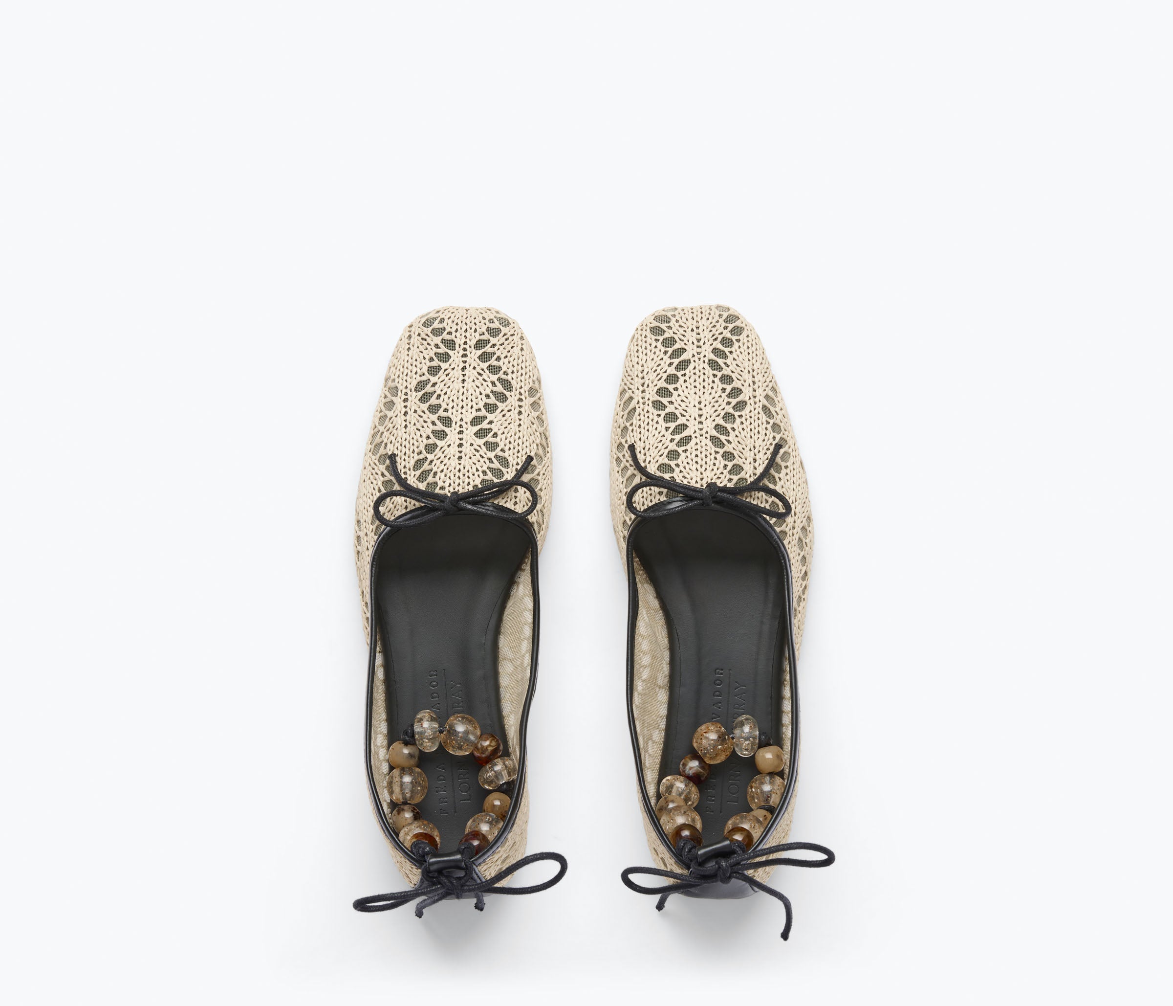 Pair of beige lace-up shoes with black soles on a white background