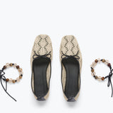 Pair of beige lace shoes with black soles on a white background, accompanied by two matching bracelets.