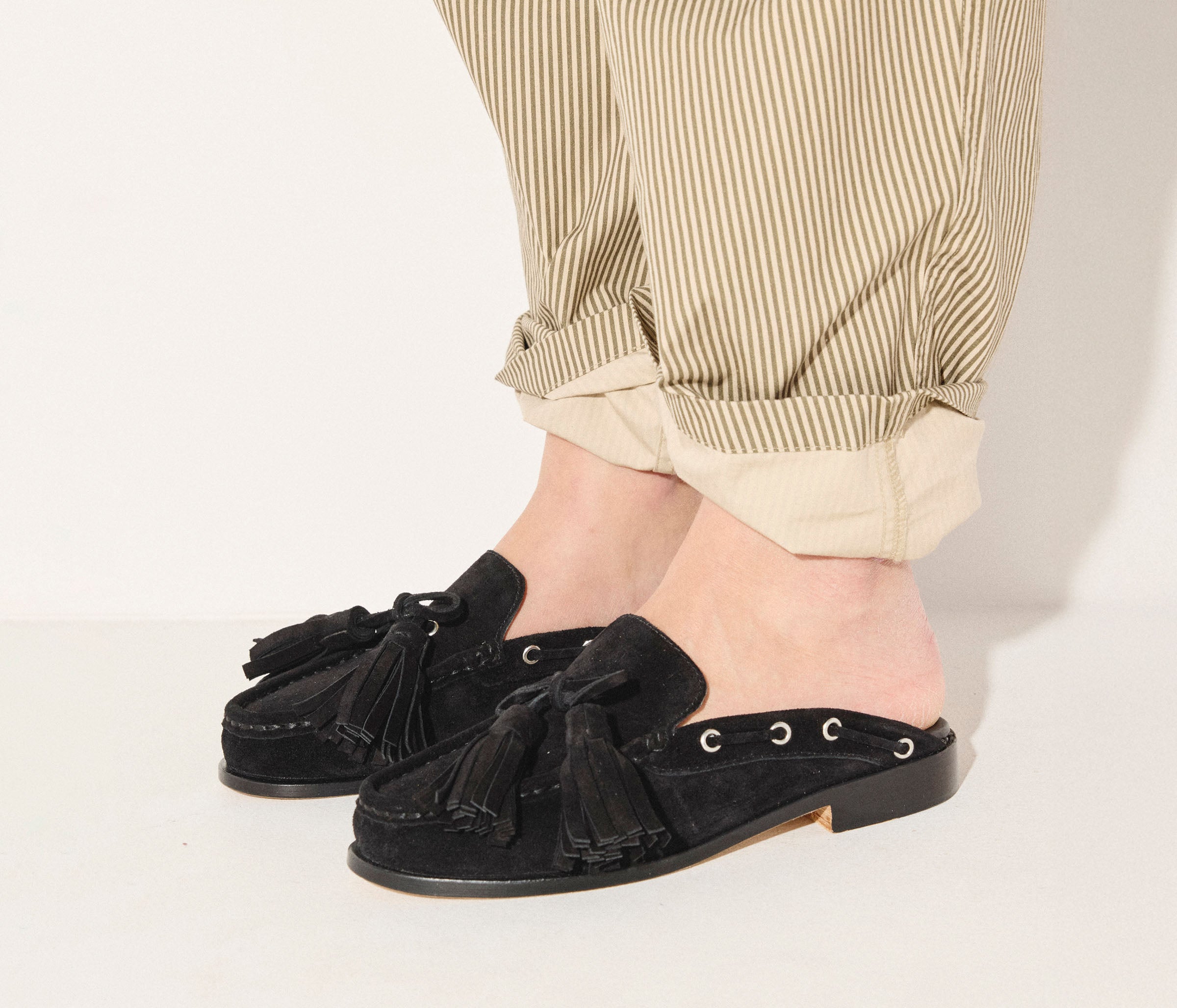 Black suede Leon tassel penny loafer mule by Freda Salvador, showcasing its sleek design and tassel details.
