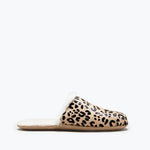 Freda Salvador James shearling slip-on slippers in tan and black, displayed outdoors on a textured surface.